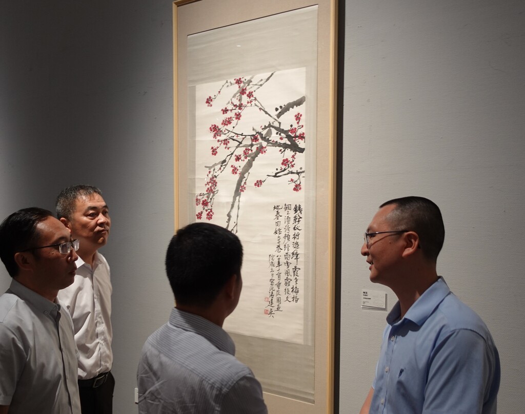 重庆美术馆（重庆画院）副馆长、副院长唐德福向观展嘉宾介绍展出中的冯建吴作品
