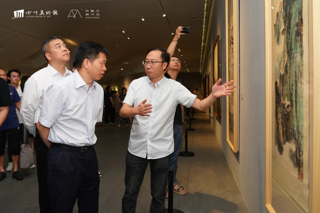 四川省文联党组副书记王忠臣（右二）、四川美术馆馆长吴晓东（右一）观看晏济元作品（图片由四川美术馆提供）